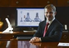 Dr. Greg Berlet seated in an office presenting ankle replacement imaging and surgical advancements.